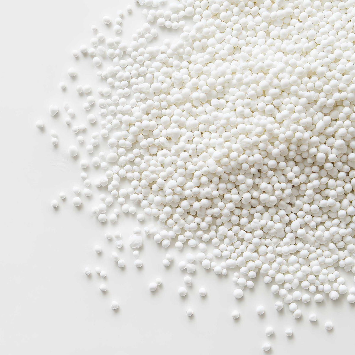 NeutrAcalC NC1054 Refill Pack of small white spherical beads, with a smooth, matte mineral-like appearance.
